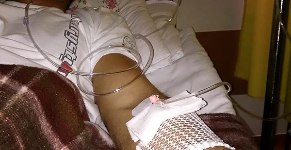 Ręka z wkłutą kroplówką na szpitalnym łóżku